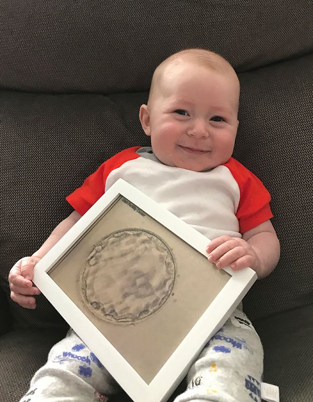 smiling baby holding a framed picture